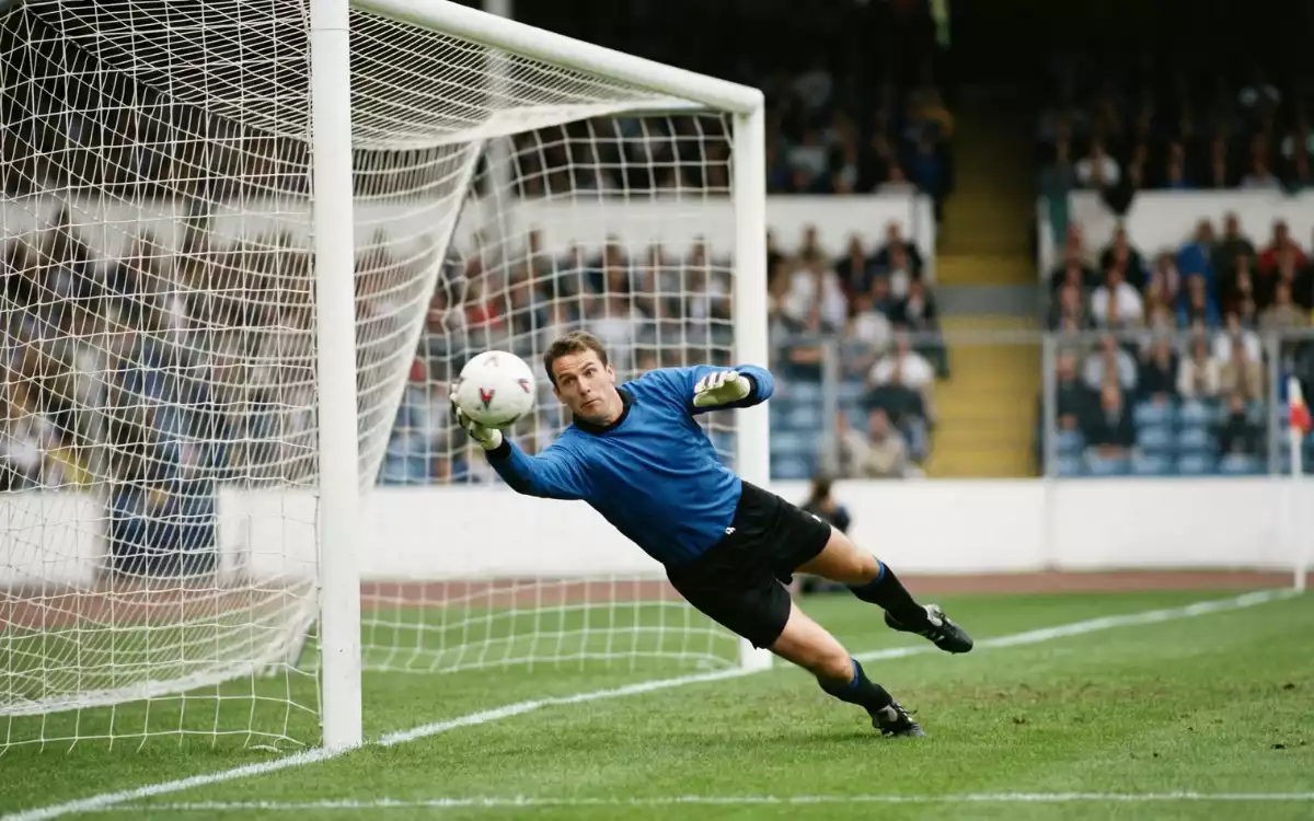 Football goalkeeper making a save to keep the match level